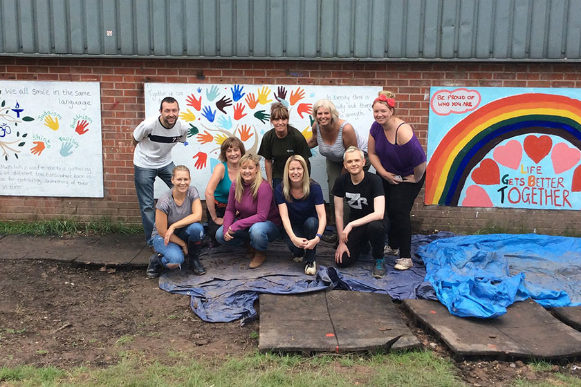 Playground team pose in front of the new murals